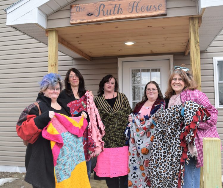 Members of the Crimson Phoenix Club showing off the handmade blankets they donated to the Ruth House