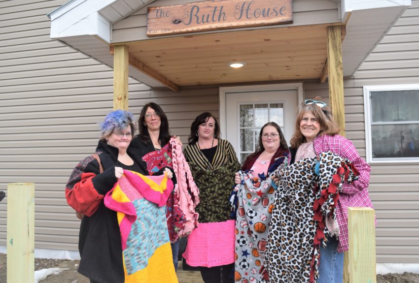 Members of the Crimson Phoenix Club showing off the handmade blankets they donated to the Ruth House