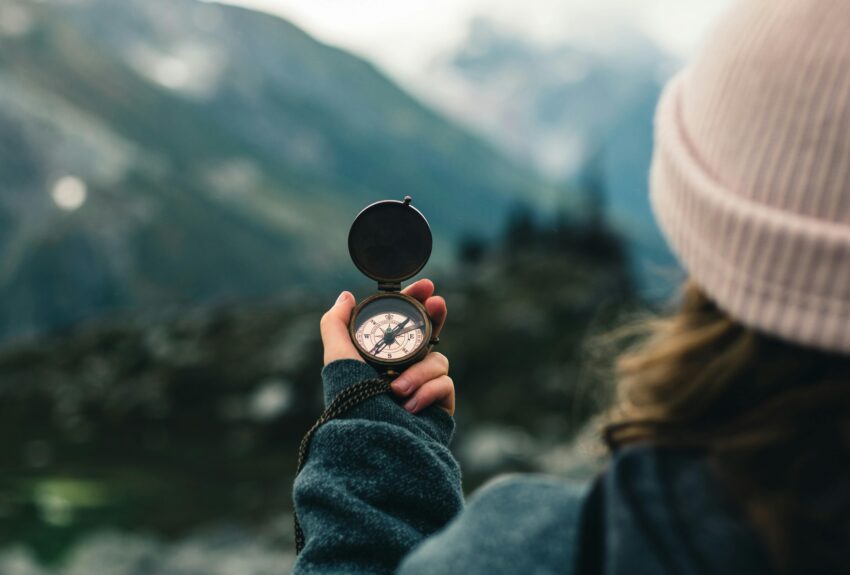 Woman standing on a mountain, holding a compass and looking toward the horizon. The image symbolizes guidance and direction, aligning with the theme "How to find the right therapist."