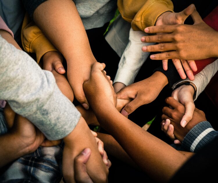 A group of people hold hands with crisscrossed arms, symbolizing unity and support. This image highlights the topic 'can addiction be treated,' emphasizing the strength of community in the recovery process.