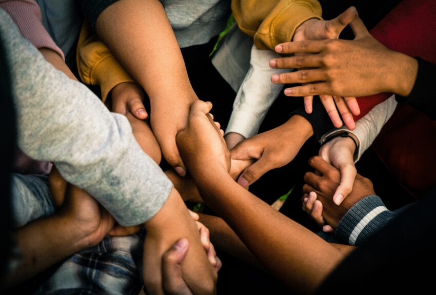 A group of people hold hands with crisscrossed arms, symbolizing unity and support. This image highlights the topic 'can addiction be treated,' emphasizing the strength of community in the recovery process.