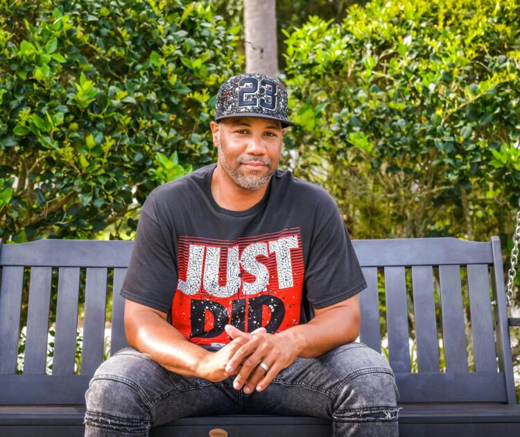 A man sits on a porch swing, contemplating whether mental health can affect physical health.