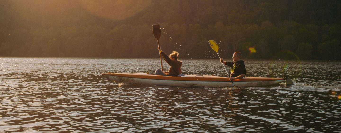 A man and woman kayak across a lake, contemplating the mental health services offered in Malone.