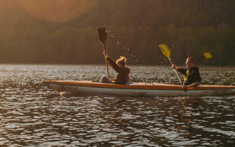 A man and woman kayak across a lake, contemplating the mental health services offered in Malone.