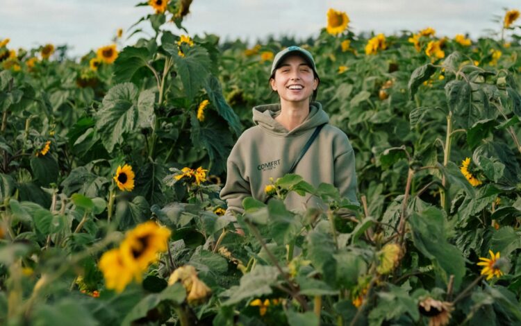 A woman stands in a field of sunflowers, symbolizing the healing and recovery provided by 24/7 mental health and addiction services.