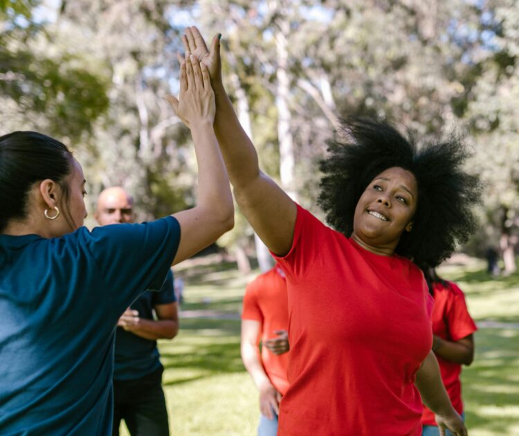 Two women high-five, celebrating the independence possible through self-direction services.