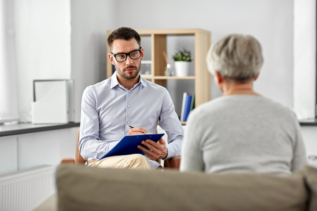 Geriatric psychology: a psychologist with clipboard taking notes and listening to a patient.