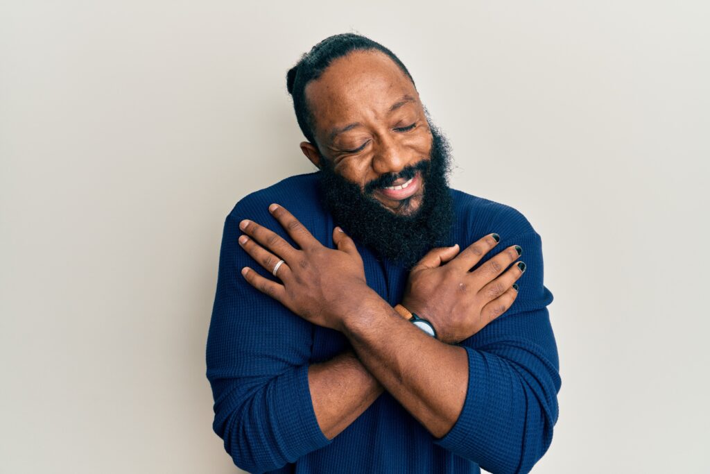 A man hugs oneself happy and positive, smiling confident because of treatment received for Obsessive-Compulsive Disorder.