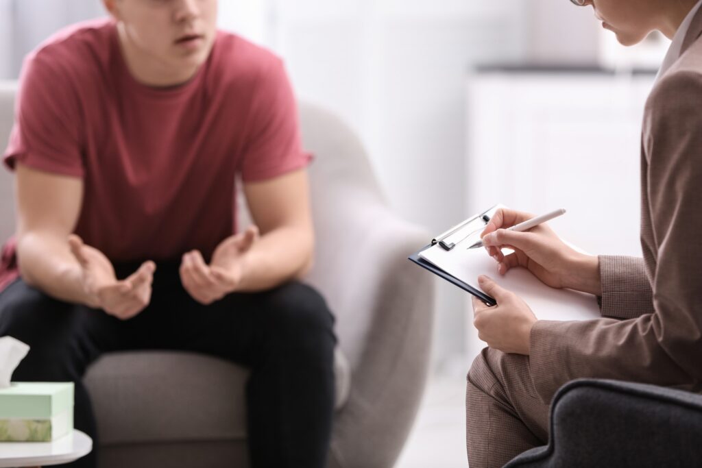 A teen boy talks with his therapist.