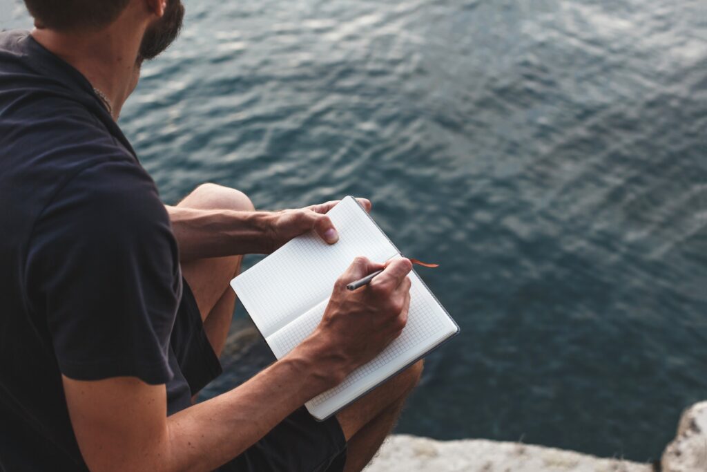 A man journals outside, an example of an alternative for mental health.