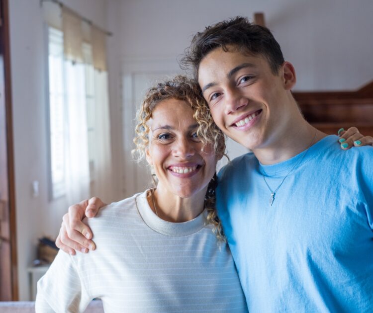 Portrait of grateful teenager man hugging his smiling middle-aged mother.