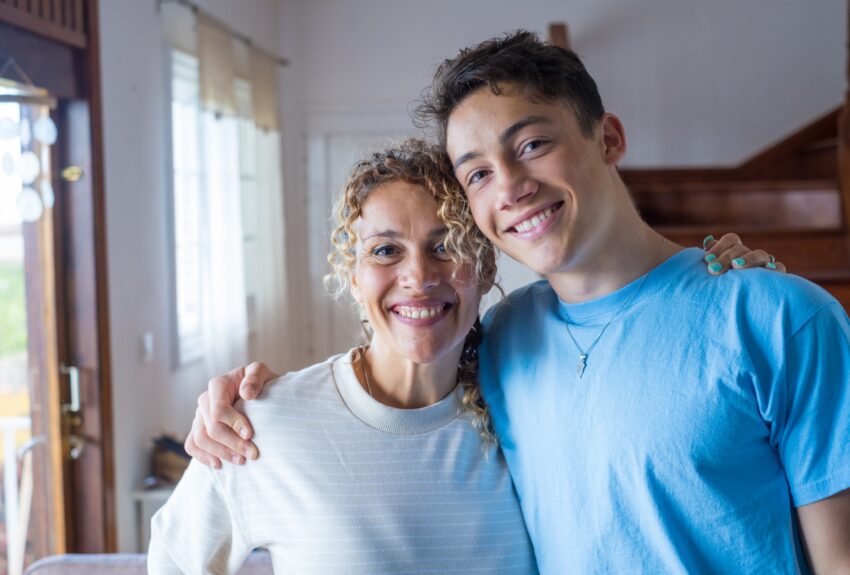 Portrait of grateful teenager man hugging his smiling middle-aged mother.