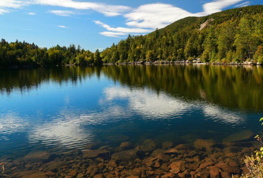 The blue sky reflects off a lake in the mountains.