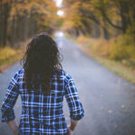 Woman walking down a road in the fall